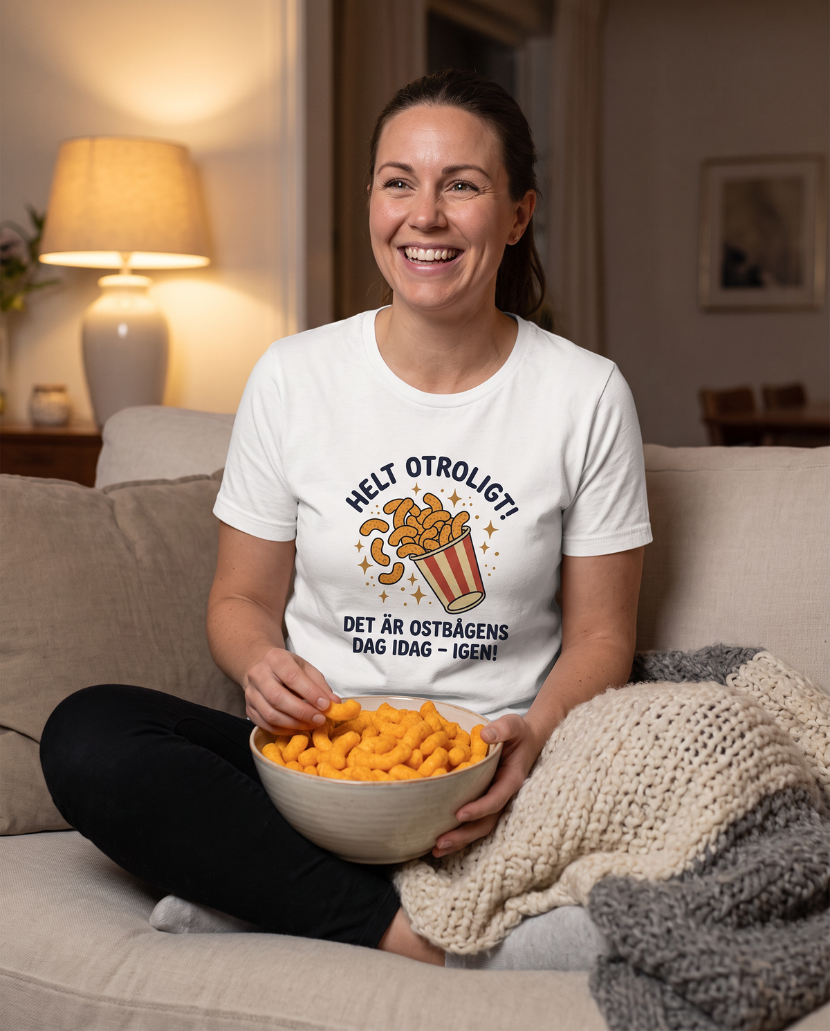 Kvinna i soffan med ostbågar i t-shirt med trycket Ostbågens dag